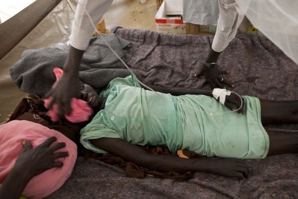Un niño en África la malaria luchando. Su cuerpo está cubierto de toallas húmedas para ayudar a traer a su fiebre.