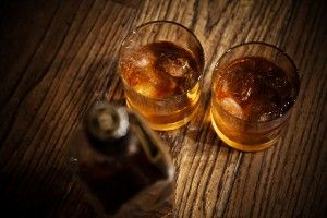 vasos de whisky y una botella sobre una mesa de madera