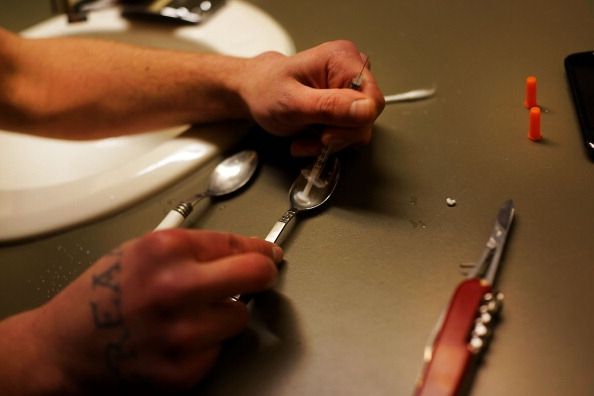Un adicto prepara una inyección de heroína.