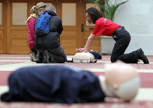Un hombre muestra dos personas cómo realizar la RCP en un maniquí.