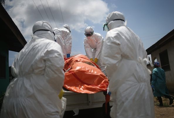Los trabajadores que manipulan el cuerpo de una víctima del Ébola en Liberia. Restricciones sanitarias han chocado con las prácticas funerarias en la vecina Guinea.