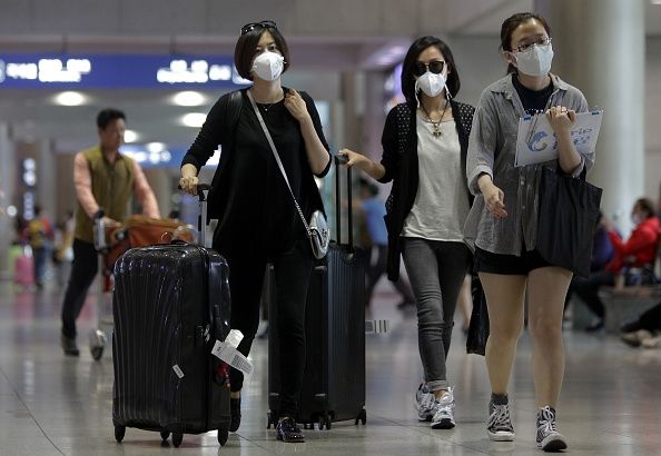 Los viajeros con máscaras debido al brote de MERS, ya que caminar a través de un aeropuerto de Corea del Sur.