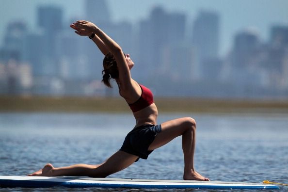 Practioners Disfrute de la serenidad de Yoga Paddleboard
